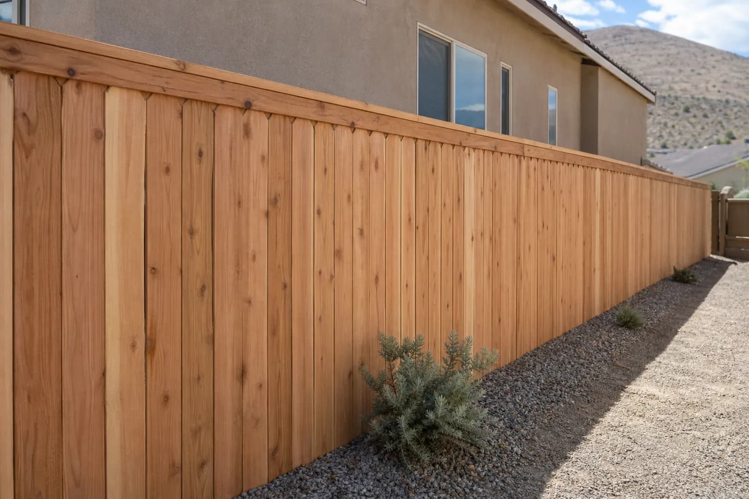 New 6-foot dog-ear cedar privacy fence with a cap rail along the side yard of a tan stucco home